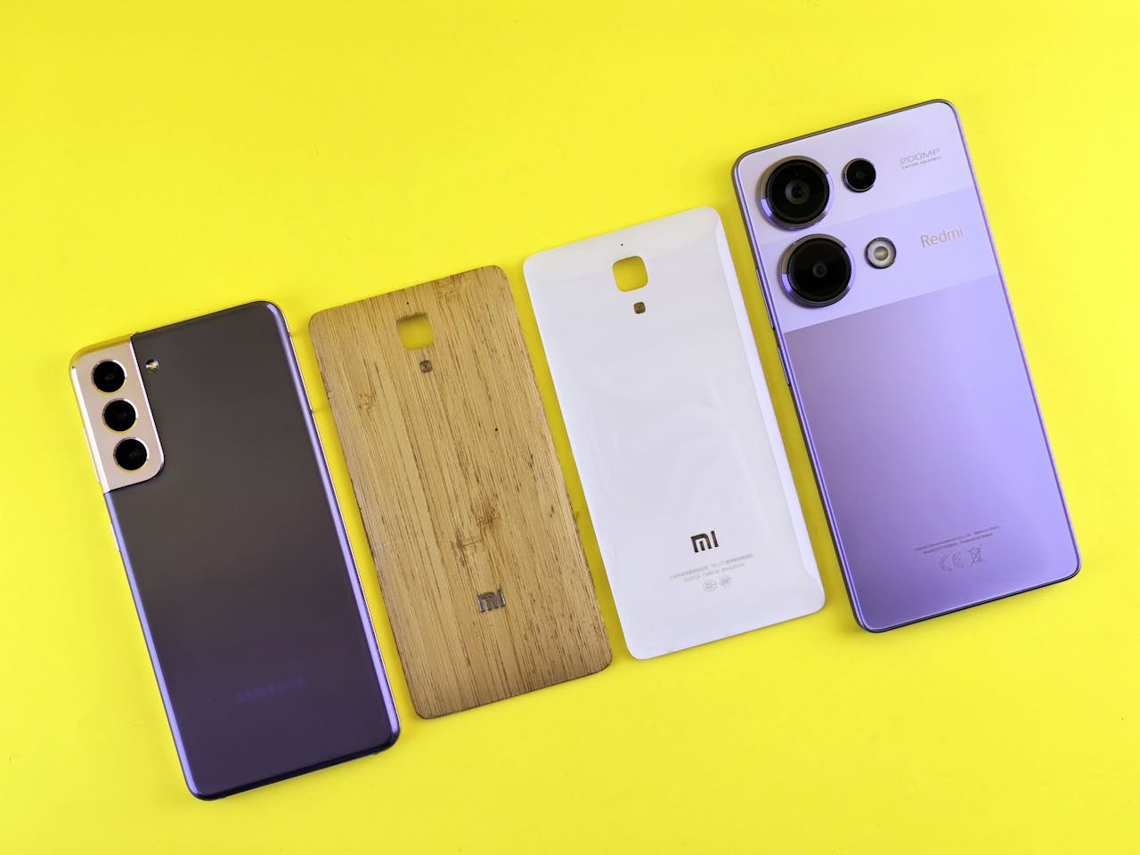A collection of different smartphone back covers displayed on a vibrant yellow surface.